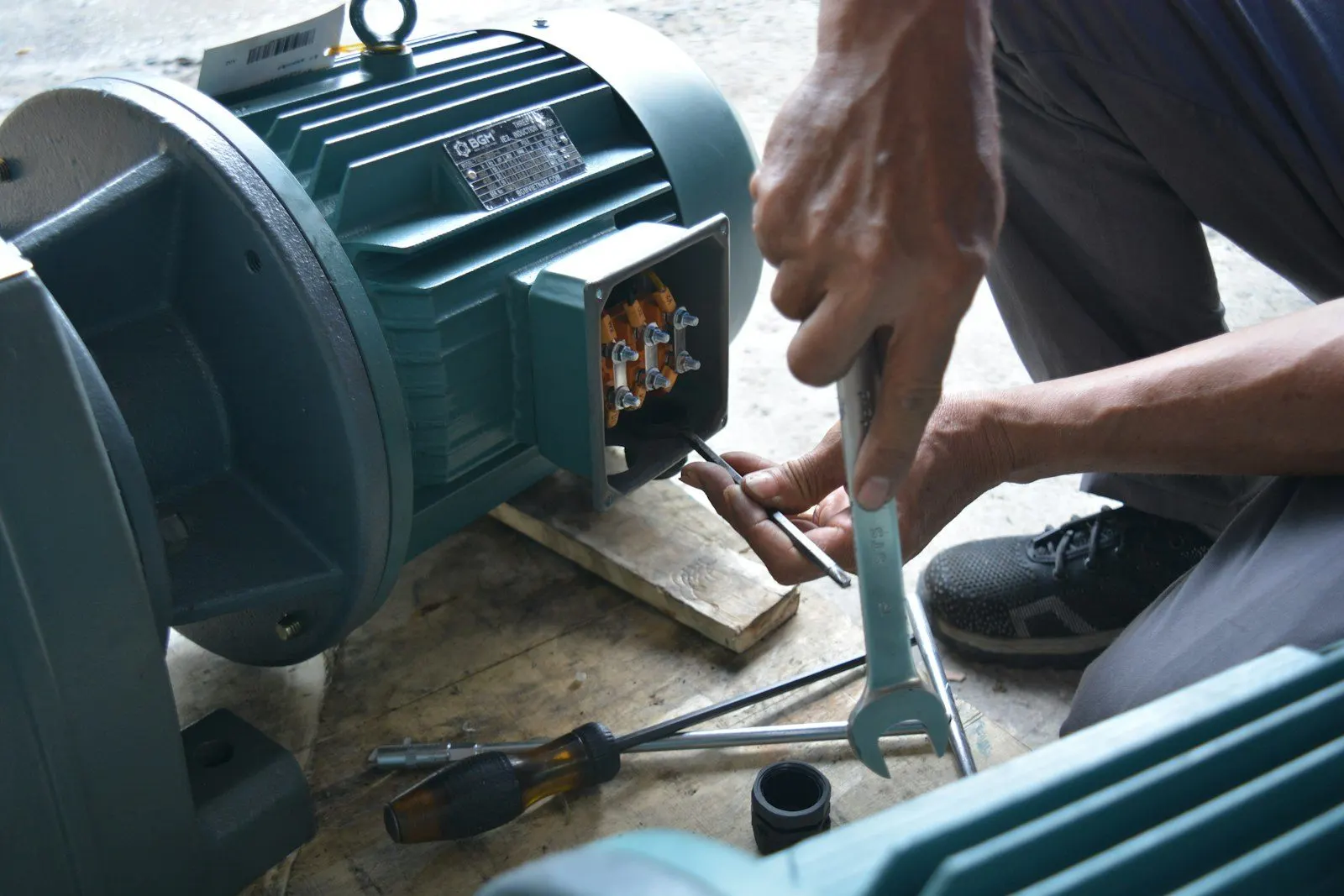 Técnico interviniendo un motor eléctrico con herramienta en el taller